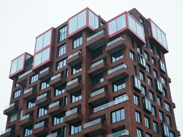 Unique red-brick apartment building with striking design in an urban setting.